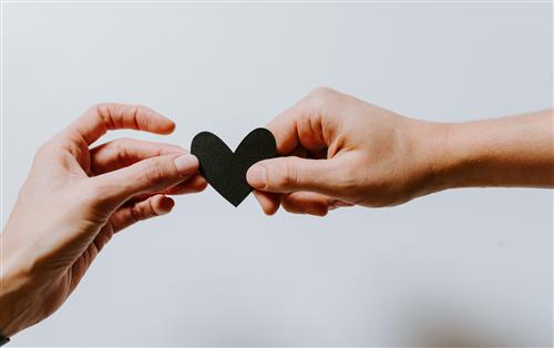 Two hands holding a paper heart cut out.Photo by Kelly Sikkema on Unsplash
