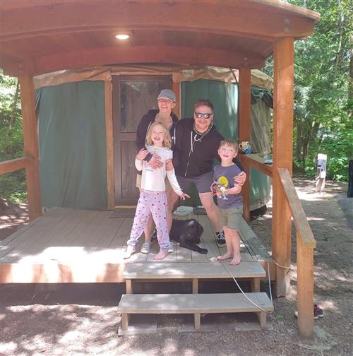 family smiles in front of a yurt