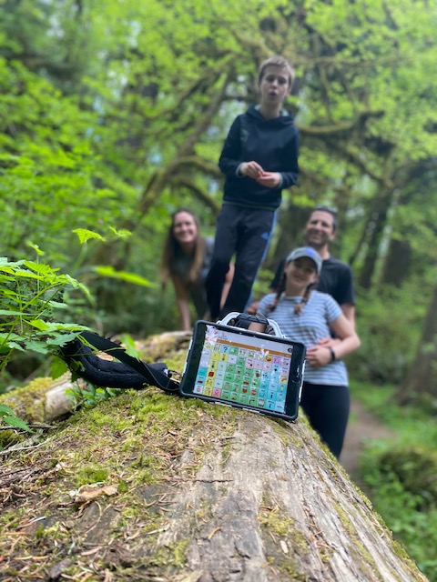 family poses around an AAC device outdoors